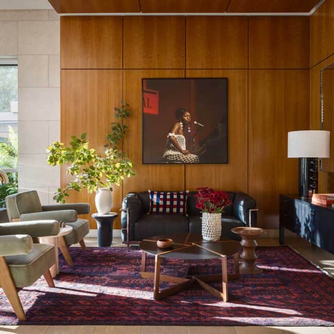 The art sets the tone in this rich and welcoming space. Nina Simone in 1968, photographed by jazz photographer David Redfern and framed by Brookside Gallery and Framing. Smart, iconic seating includes lounge chairs originally designed by Pierre Jeanneret, the cousin of Le Corbusier, and a leather LC2 sofa, designed in 1928 by his younger female protege, Charlotte Perriand, which sits adjacent. Unique steel scalloped Arcs mirrors are by HAY, via DWR, and the placement of sculptural pieces, including a large Kelly Wearstler lamp for Visual Comfort, adds personal touches.