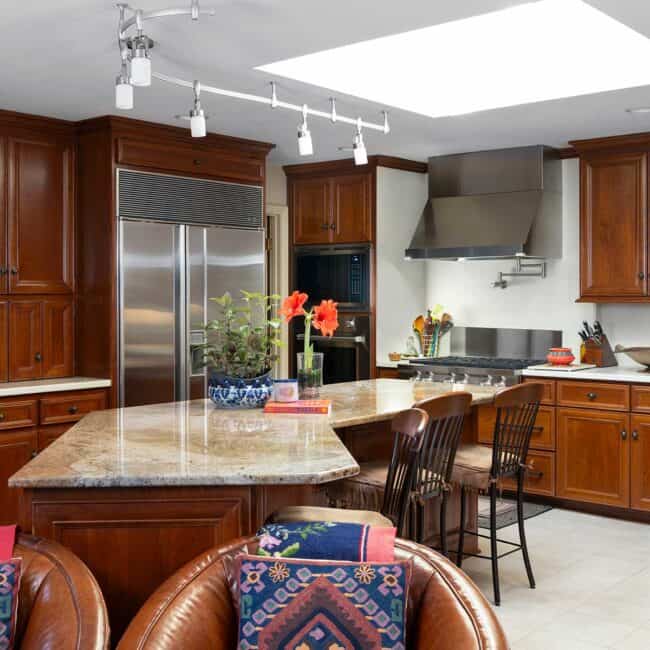 The Mukharjis remodeled the kitchen in the early 2000s, installing a skylight that floods the space with natural light and balancing the warm wood tones of the cabinets. This is where Mukharji holds classes for those who sign up to learn the art of American Indian cooking. The space also includes an adjacent dining room and sitting room in front of a hearth, where Mukharji spends most of her time.