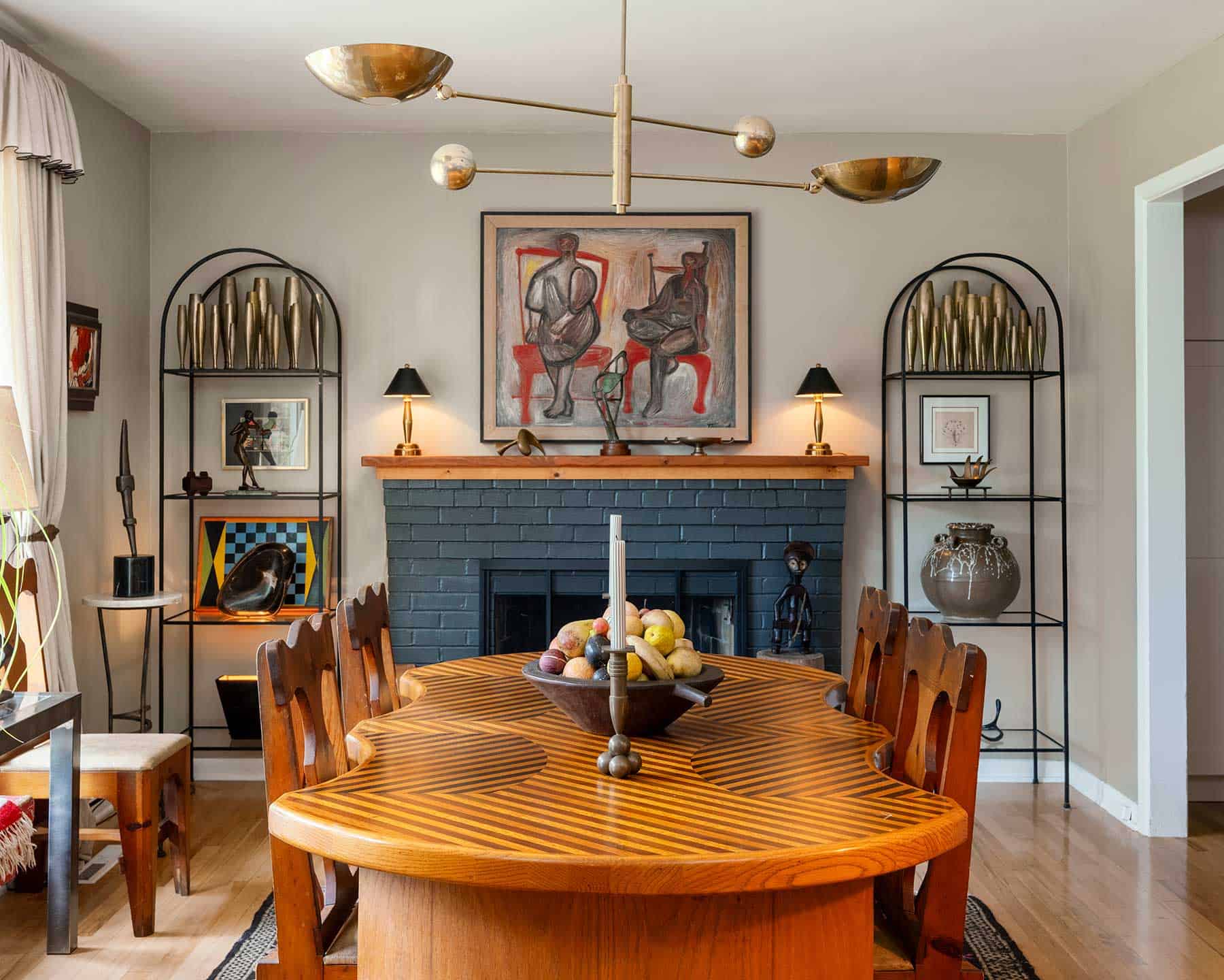 In the dining room, a 1950s abstract by St. Louis artist Kenneth Trueblood sits above the mantle. The unique dining table with its custom inlaid top is from the ’70s. The French art deco étagères hold Ford’s large collection of bronze deco Dirigold bud vases.