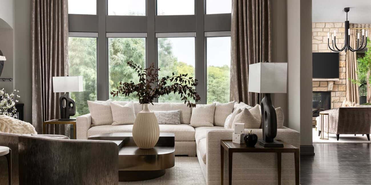 Soft drapery and tailored seating pull the wooded view into conversation.