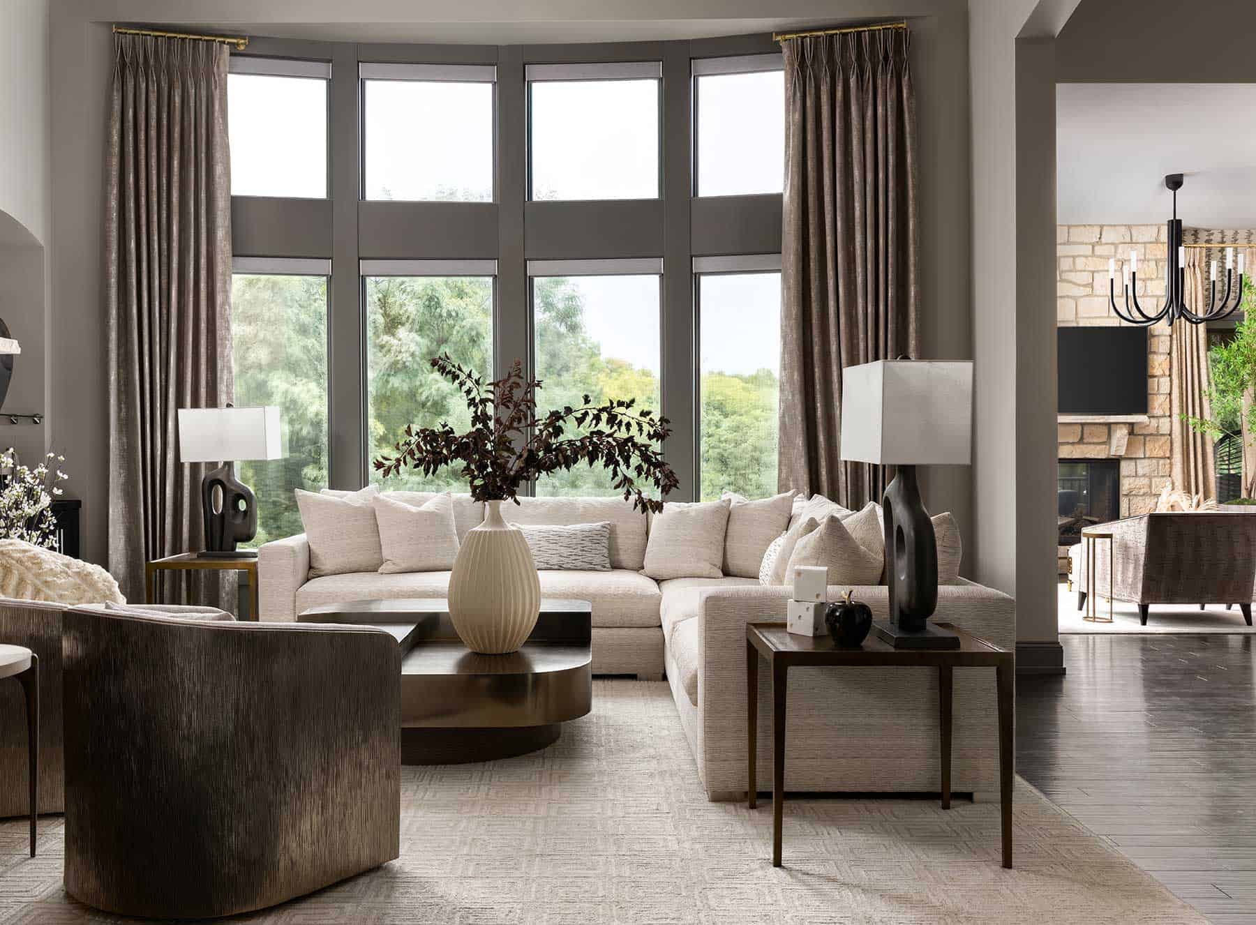 Soft drapery and tailored seating pull the wooded view into conversation.